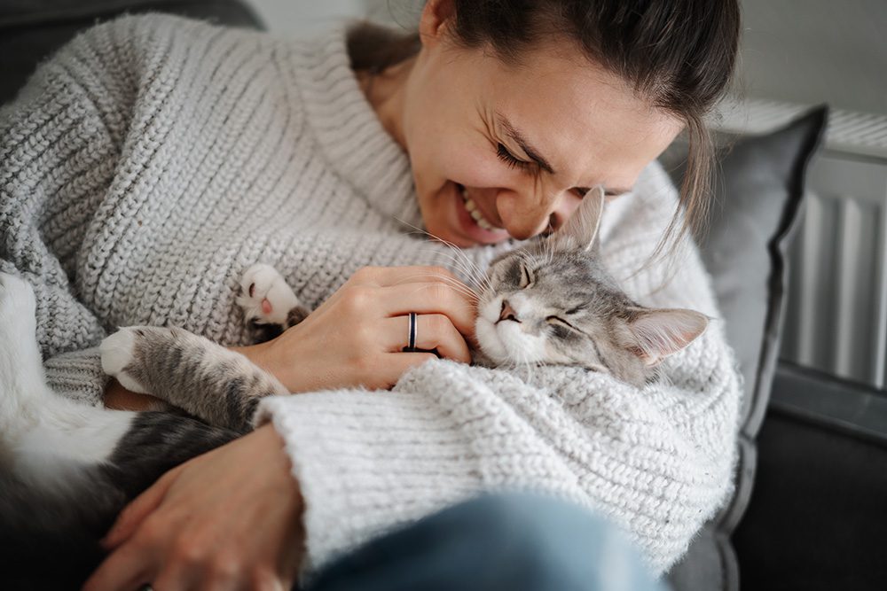 woman cuddling cat in arms
